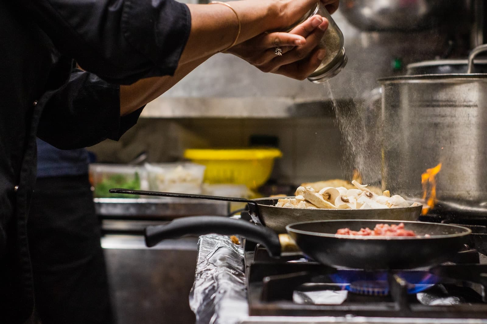 person pouring seasoning on food