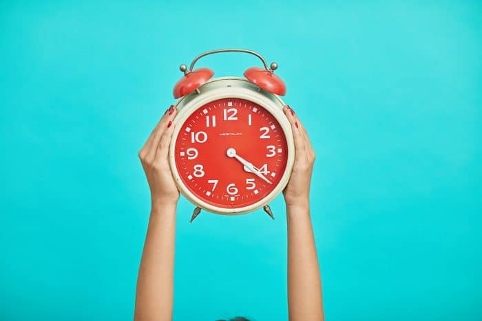 Que faire si j’ai oublié de faire ma demande de bourse au Crous ? 1 person holding red and beige twin bell analog alarm clock